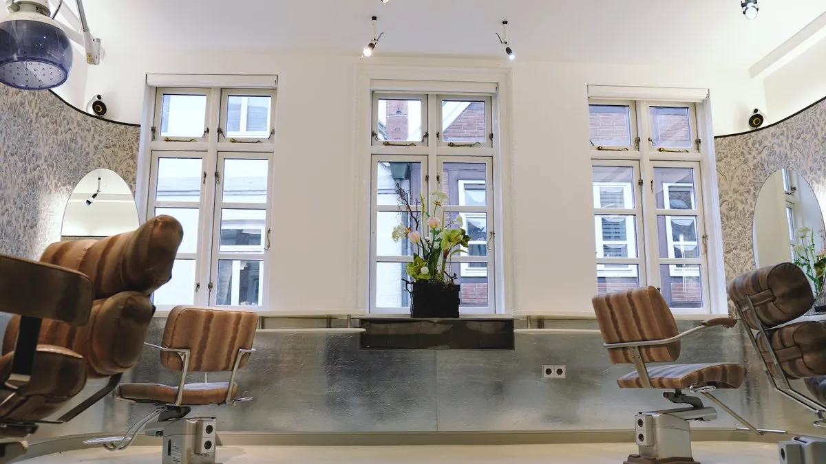Heller Salonraum mit hohen Altbaufenstern und gepolsterten Friseurstühlen